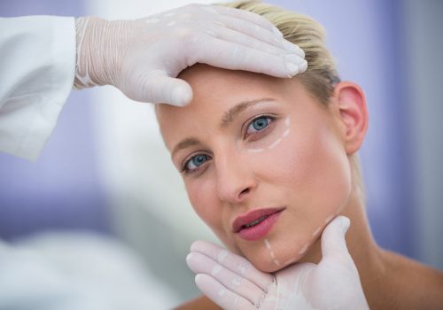 Close-up of doctor examining female patients face for cosmetic treatment